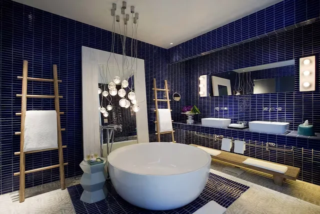 Imagem de banheira branca, redonda, em banheiro com azulejos azuis. 