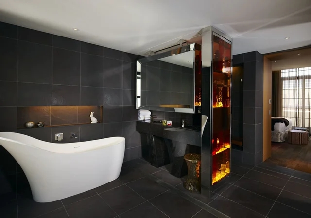 Imagem de banheira branca do Hotel QT Sydney, com azulejos pretos atrás.